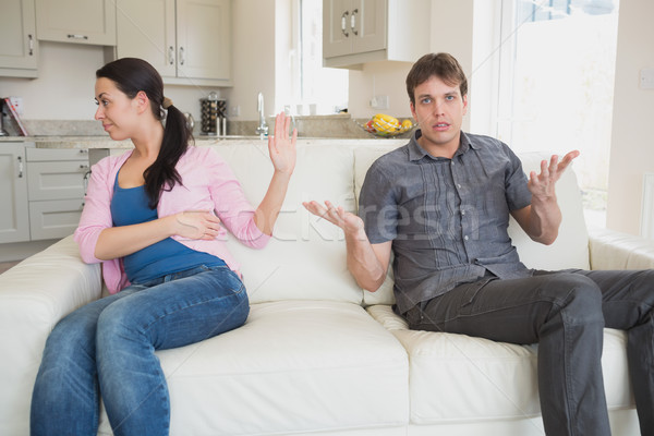 Stock photo: Two people sitting on the couch in the living room while waving each other away