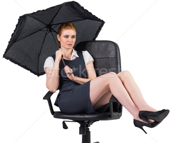 Businesswoman holding umbrella sitting on swivel chair Stock photo © wavebreak_media