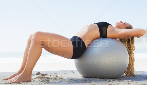 Fit blonde stretching her back on exercise ball at the beach Stock photo © wavebreak_media