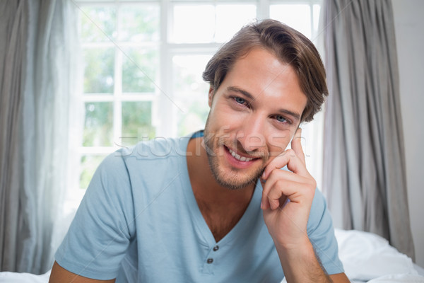 Handsome smiling man sitting on bed looking at camera Stock photo © wavebreak_media