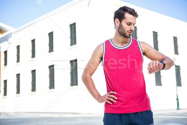 Handsome athlete checking time with hands on hips Stock photo © wavebreak_media
