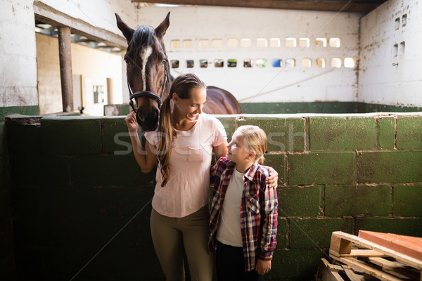 Stock photo: Sisters talking while standing by horse