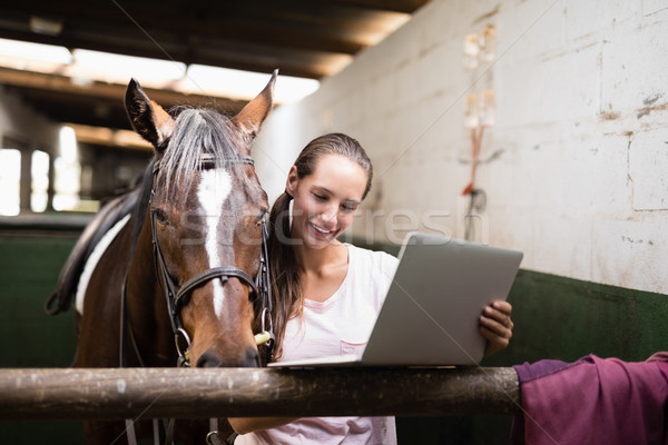 微笑 女 騎師 使用筆記本電腦 常設 馬 商業照片 © wavebreak_media