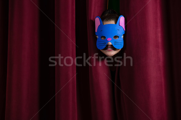 Stock photo: Ballet dancer wearing mask peeking through a stage curtain