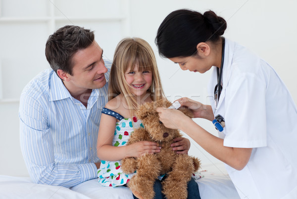 Smiling patient examining a teddy bear with a doctor Stock photo © wavebreak_media