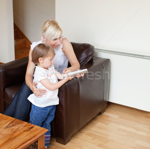 Girl holding a remote control standing in the living room Stock photo © wavebreak_media