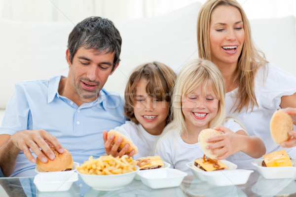 Loving family eating hamburgers sitting on sofa Stock photo © wavebreak_media