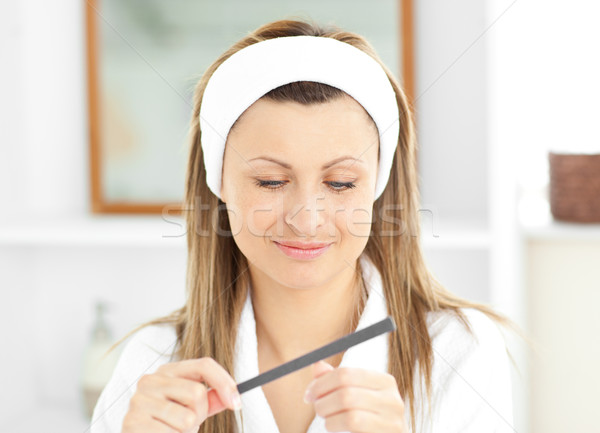 Happy woman using a nail file wearing a bath robe standing in the bathroom at home Stock photo © wavebreak_media
