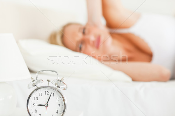 Tired woman awaked by her alarm clock in her bedroom Stock photo © wavebreak_media