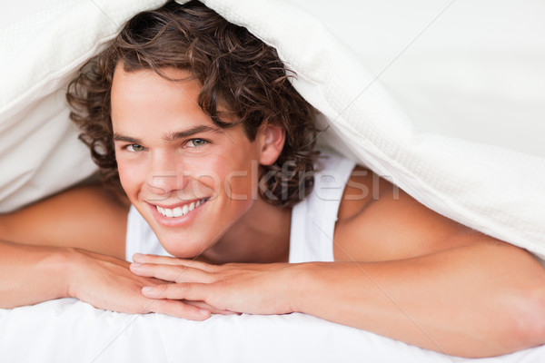 Man under a duvet with a knowing smile in a bed Stock photo © wavebreak_media