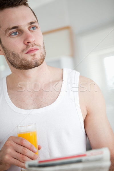 Portrait of a good looking man drinking orange juice while reading the news in his kitchen Stock photo © wavebreak_media
