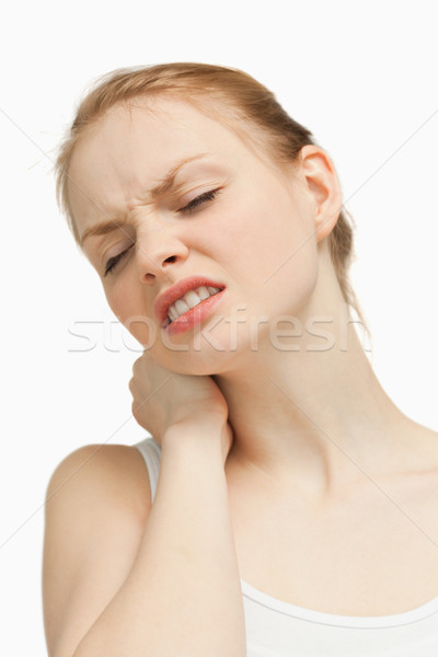 Young woman massaging her painful nape against white background Stock photo © wavebreak_media