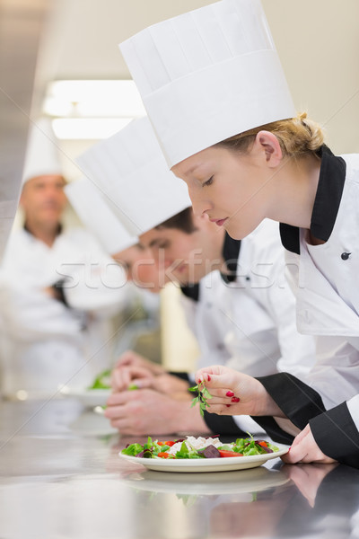 Chef's applying finishing touches to salads as head chef is watching Stock photo © wavebreak_media