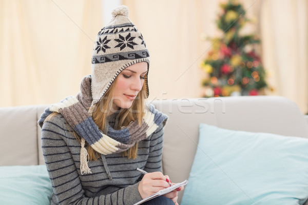 Pretty blonde with winter hat on writing on her notebook Stock photo © wavebreak_media