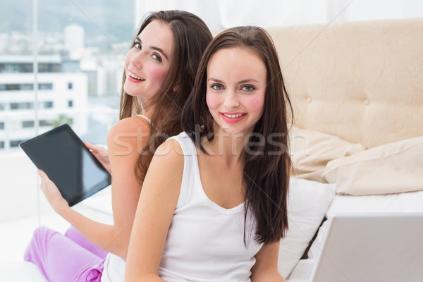 Pretty friends using their technology on bed Stock photo © wavebreak_media