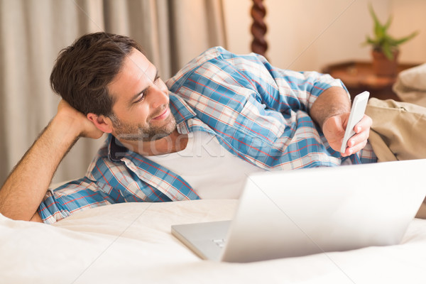 Handsome man relaxing on his bed with laptop Stock photo © wavebreak_media