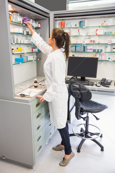 Junior pharmacist taking medicine from shelf Stock photo © wavebreak_media