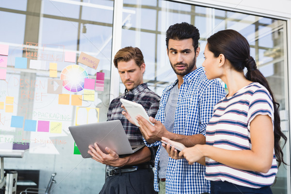 Gens d'affaires comprimé bureau permanent mur [[stock_photo]] © wavebreak_media