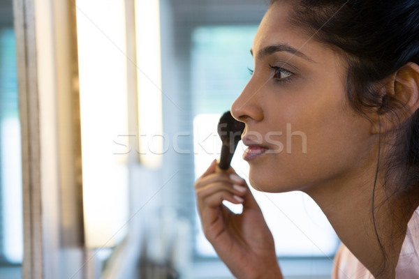 Jeune femme maquillage maison salle de bain [[stock_photo]] © wavebreak_media