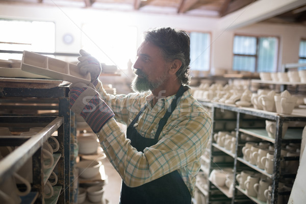Stock photo: Male potter placing craft product on shelf
