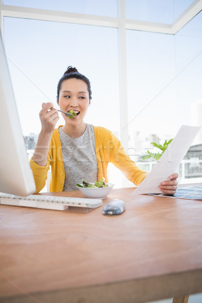 A beautiful businesswoman eating and reading Stock photo © wavebreak_media