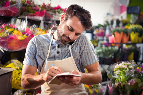 Male florist noting order in diary while talking on mobile phone Stock photo © wavebreak_media