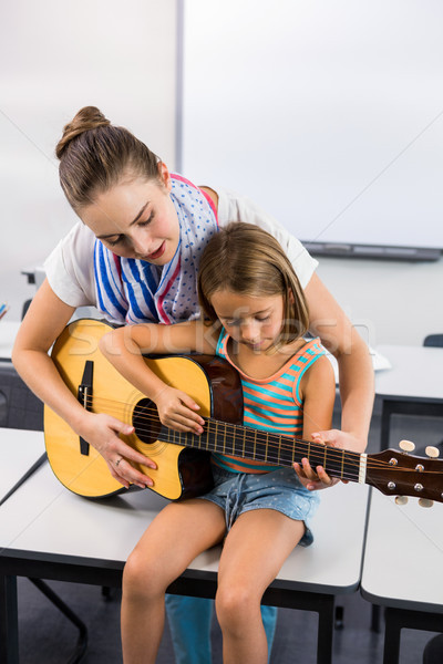 Teacher assisting girl to play guitar in classroom Stock photo © wavebreak_media