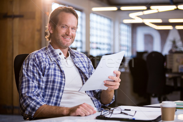 Businessman holding documents while sitting at desk Stock photo © wavebreak_media