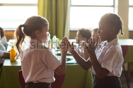 Schoolgirls playing clapping game in canteen Stock photo © wavebreak_media