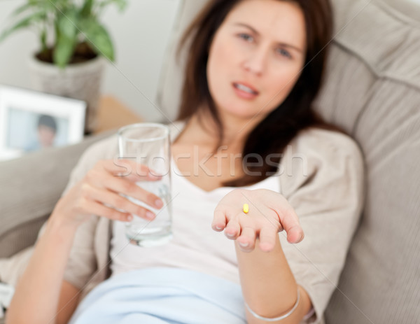 Close up of a woman taking her medicine on the sofa at home Stock photo © wavebreak_media