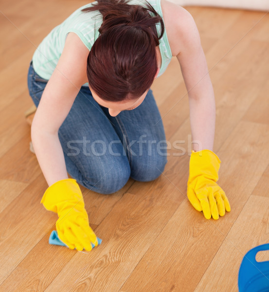 Attractive red-haired woman cleaning the floor while kneeling at home Stock photo © wavebreak_media