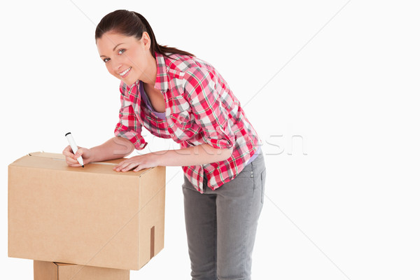 Beautiful woman writing on cardboard boxes with a marker while standing against a white background Stock photo © wavebreak_media