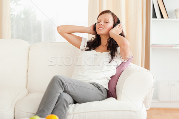 Bonitinho mulher relaxante sofá ouvir música sala de estar Foto stock © wavebreak_media