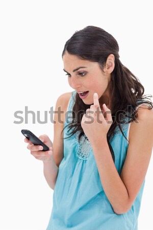 Stock photo: Portrait of an amazed woman reading a text message against a white background