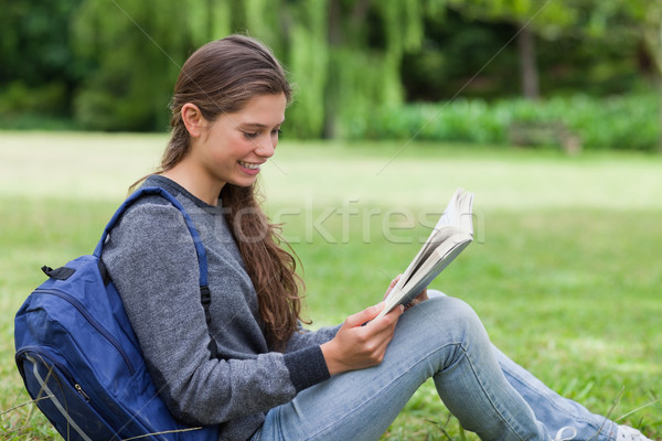 Young calm girl sitting on the grass while attentively reading a book Stock photo © wavebreak_media