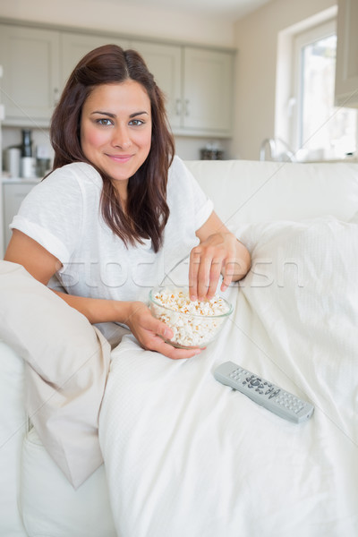 Stock photo: Brunette woman eating popcorn in front of the television