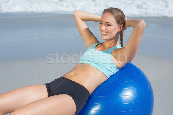 Stock photo: Fit woman lying on exercise ball at the beach doing sit ups