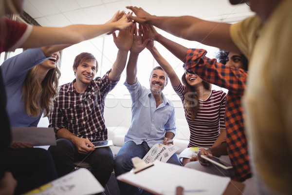 Stock photo: Cheerful business people giving high five while sitting creative office