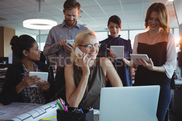 Smiling business colleagues using mobile phones and digital tablets together Stock photo © wavebreak_media