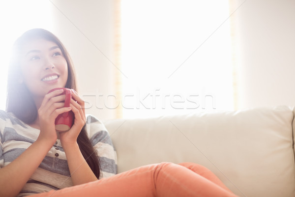 Zâmbitor asiatic femeie canapea bautura fierbinte acasă Imagine de stoc © wavebreak_media