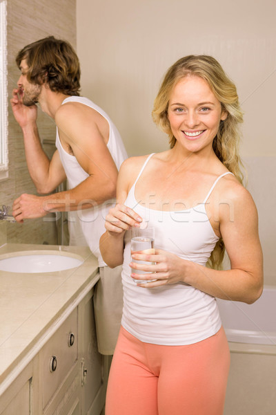 Blonde woman taking a pill with her boyfriend brushing his teeth Stock photo © wavebreak_media