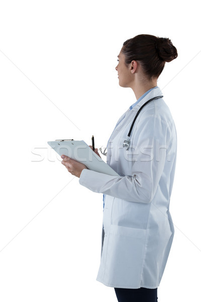 Stock photo: Female doctor holding clipboard and looking away