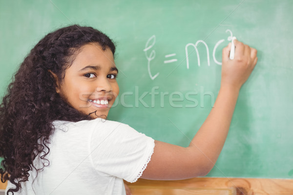 Smiling pupil writing on chalkboard in a classroom Stock photo © wavebreak_media