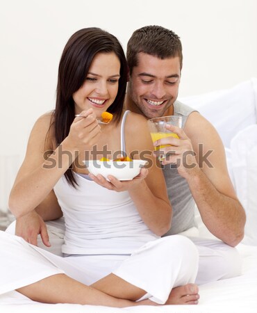 Joyful couple eating pancakes lying on their bed Stock photo © wavebreak_media