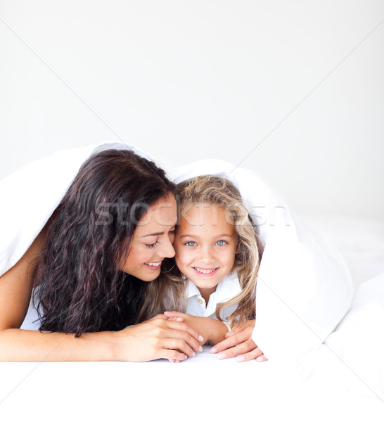 Stock photo: Attentive mother embracing her daughter lying on a bed 