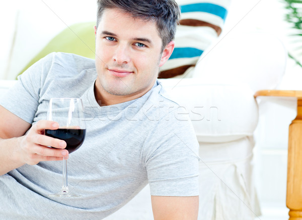 Charming caucasian man holding a wineglass in the living-room smiling at the camera Stock photo © wavebreak_media