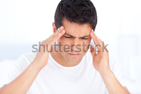 Stock photo: Portrait of a sick man having a migraine sitting in his bedroom