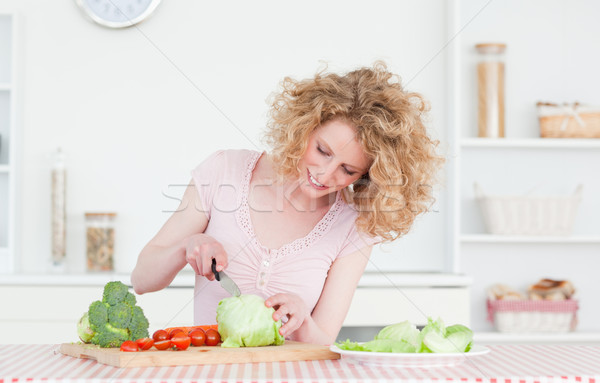 Stock photo: Charming blonde woman cooking some vegetables in the kitchen in her appartment