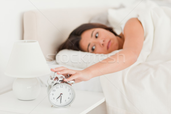 cute woman waking under sheet turning off alarm clock in bedroom Stock photo © wavebreak_media