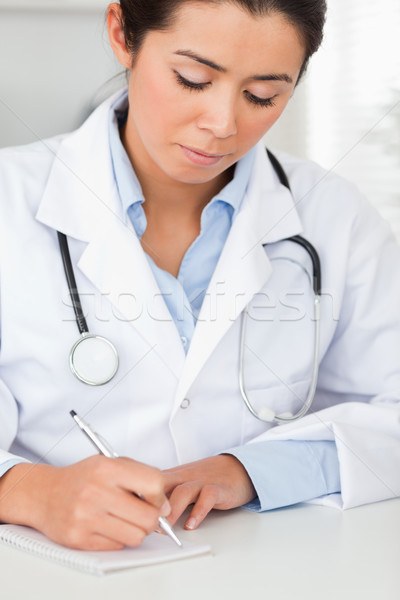 Attractive female doctor writing on a scratchpad in her office Stock photo © wavebreak_media